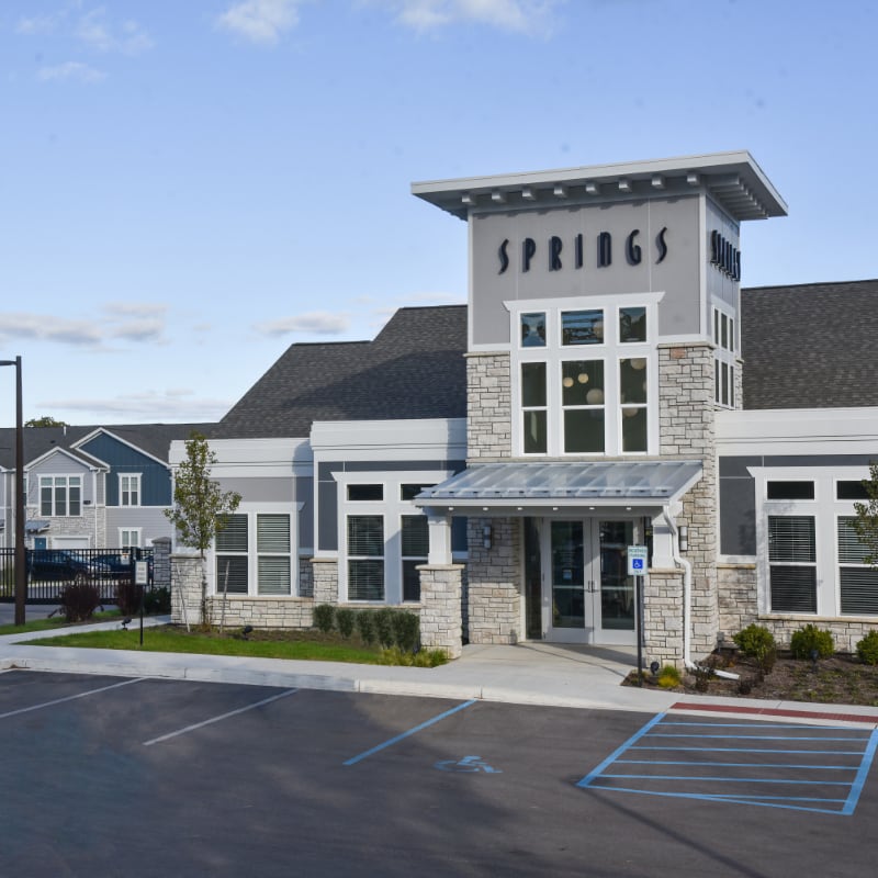 Springs clubhouse exterior with stone facade and glass awning